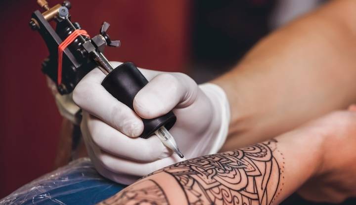 Een tatoeëermachine bestaat uit metalen onderdelen waaronder een bankschroef, een schroef, een handvat, een houder, een naaldhouder, en een geleidend paar spoelen en veren